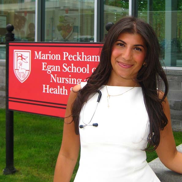 Felicia Mazzone standing in front of the Fairfield Egan building and sign after graduating with her BS in Nursing.